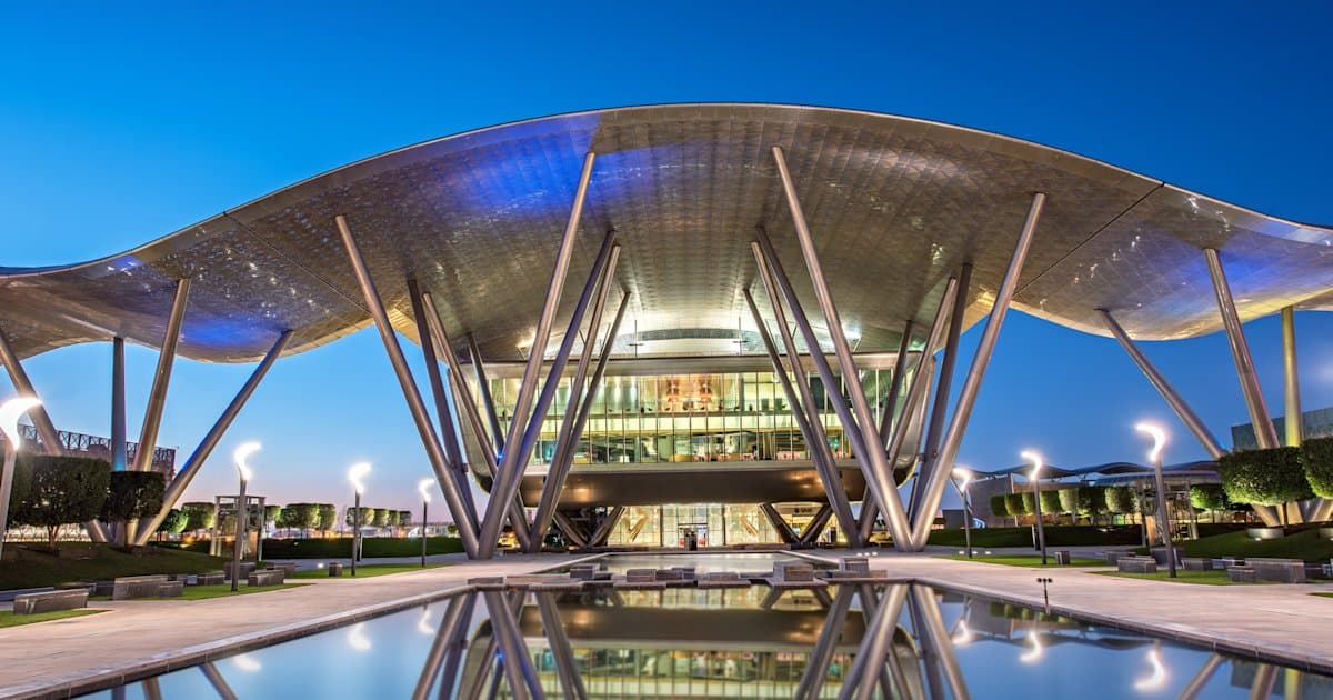 Qatar Science and Technology Park building at Qatar Foundation, illuminated at dusk.